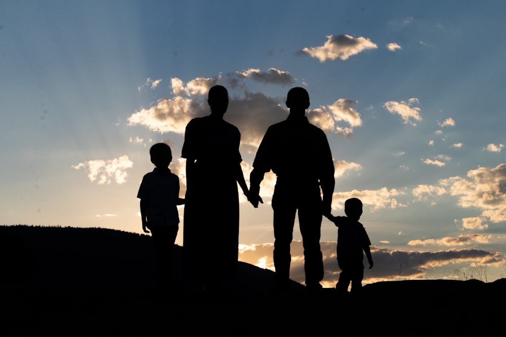 a group of people standing on a hill looking at the sunset