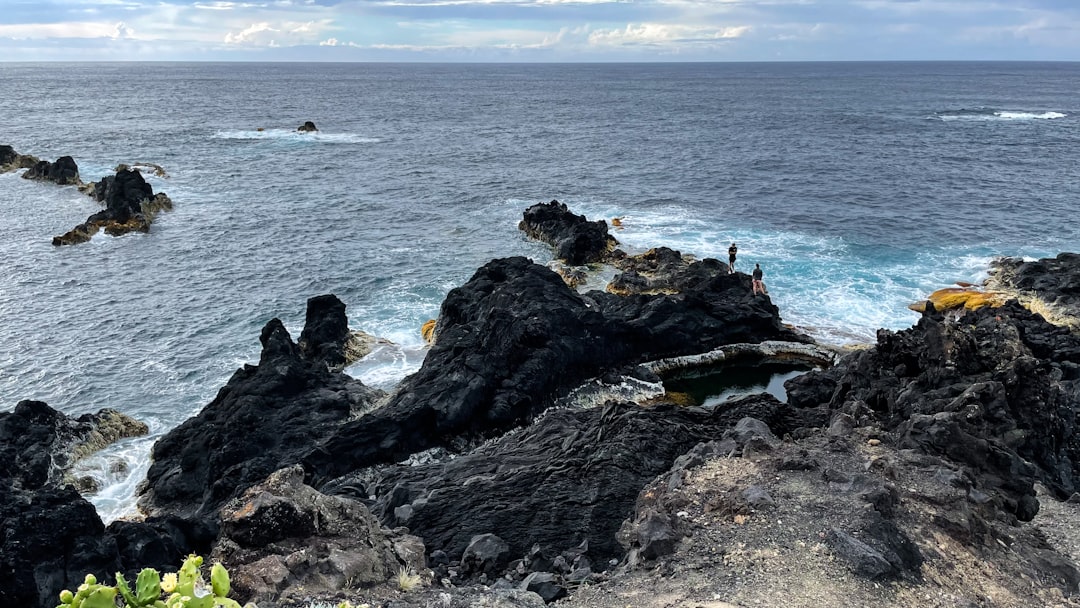 a rocky beach with people on it with Black Rocks in the background,