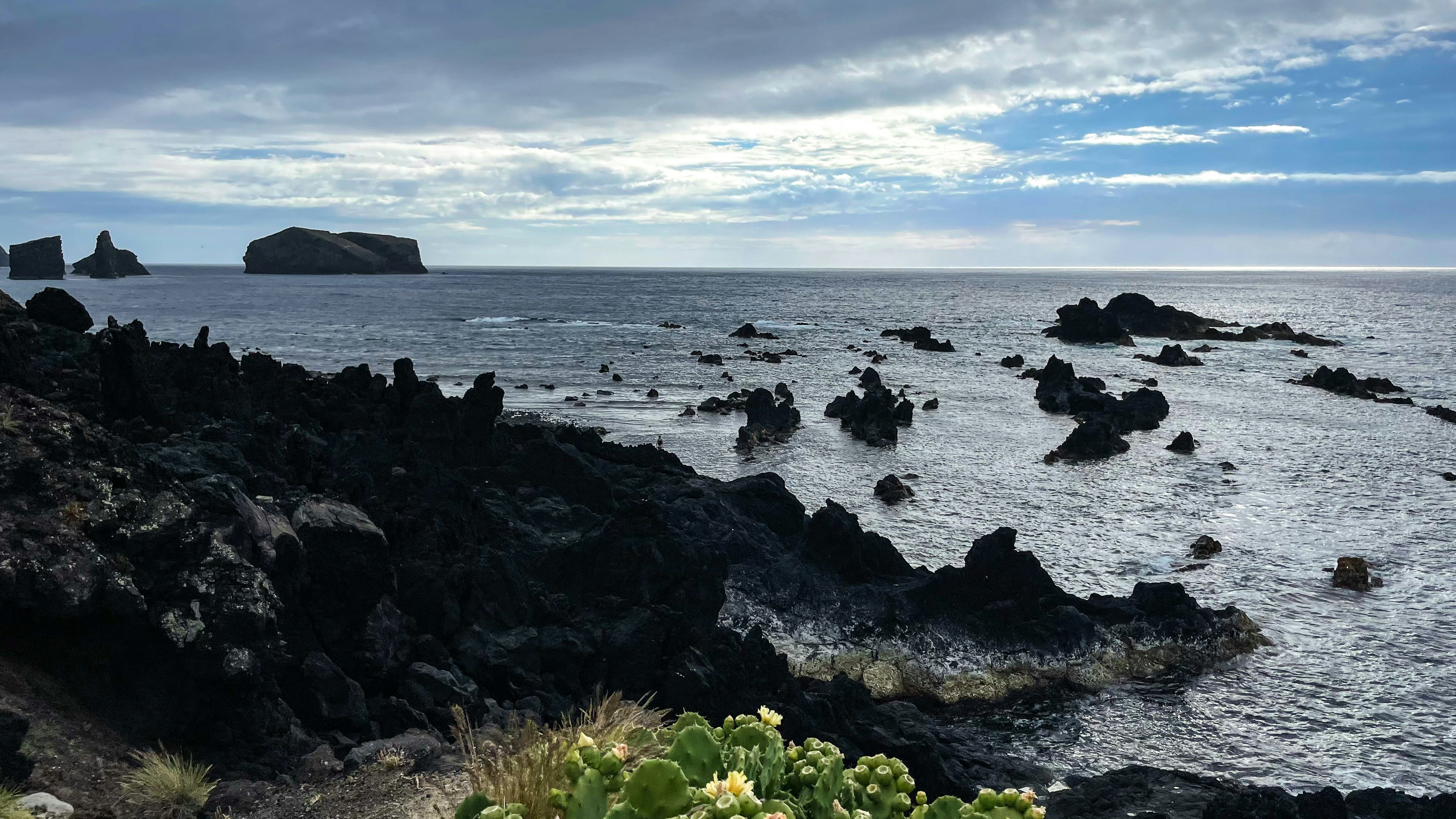 a rocky beach with a body of water in the background, 