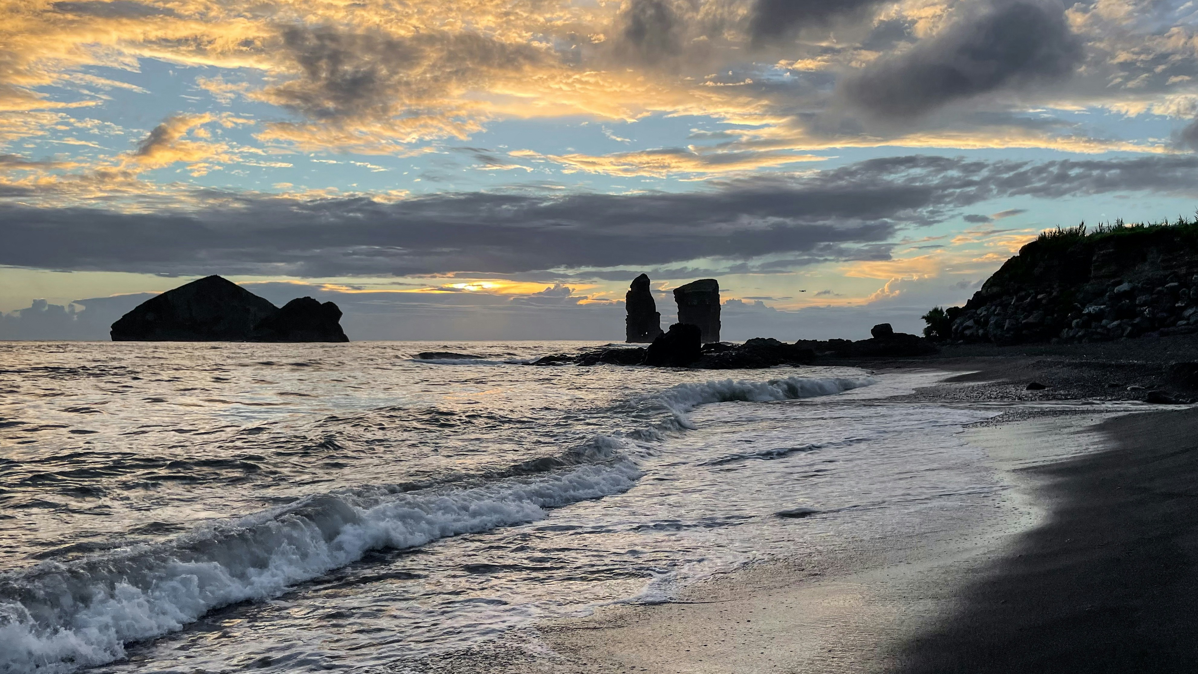 a beach with rocks and water, 