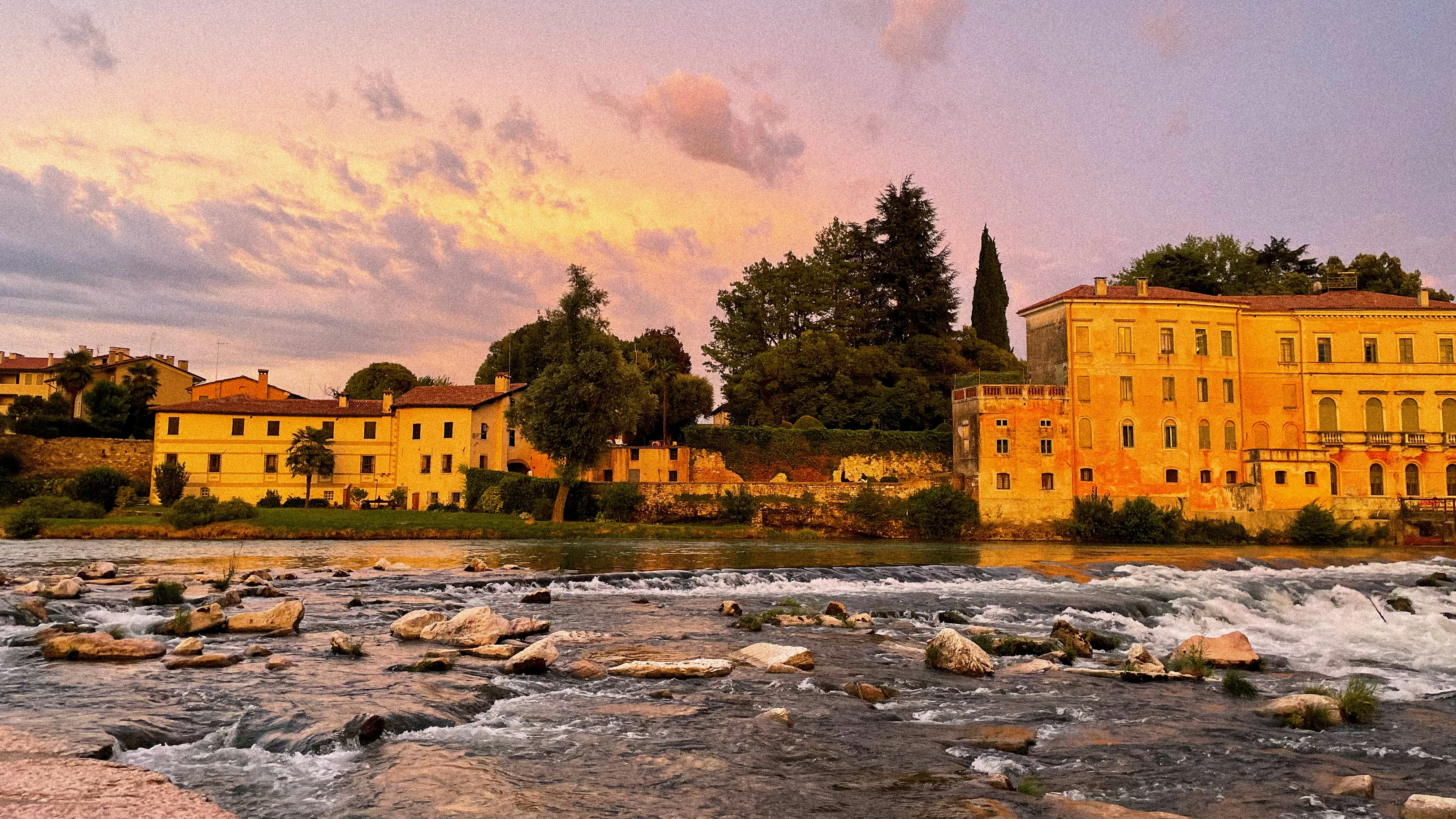 a river with rocks and buildings along it, 