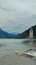 Close-up of the ancient bell tower partially submerged, surrounded by calm reflective waters.