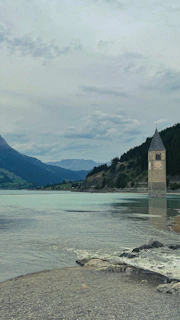 Close-up of the ancient bell tower partially submerged, surrounded by calm reflective waters.