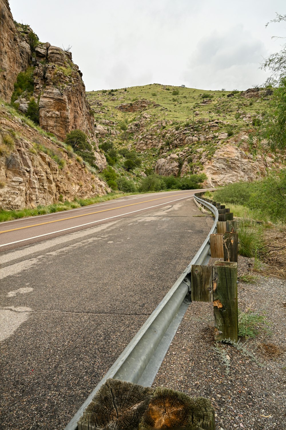 a road with a fence and rocks on the side