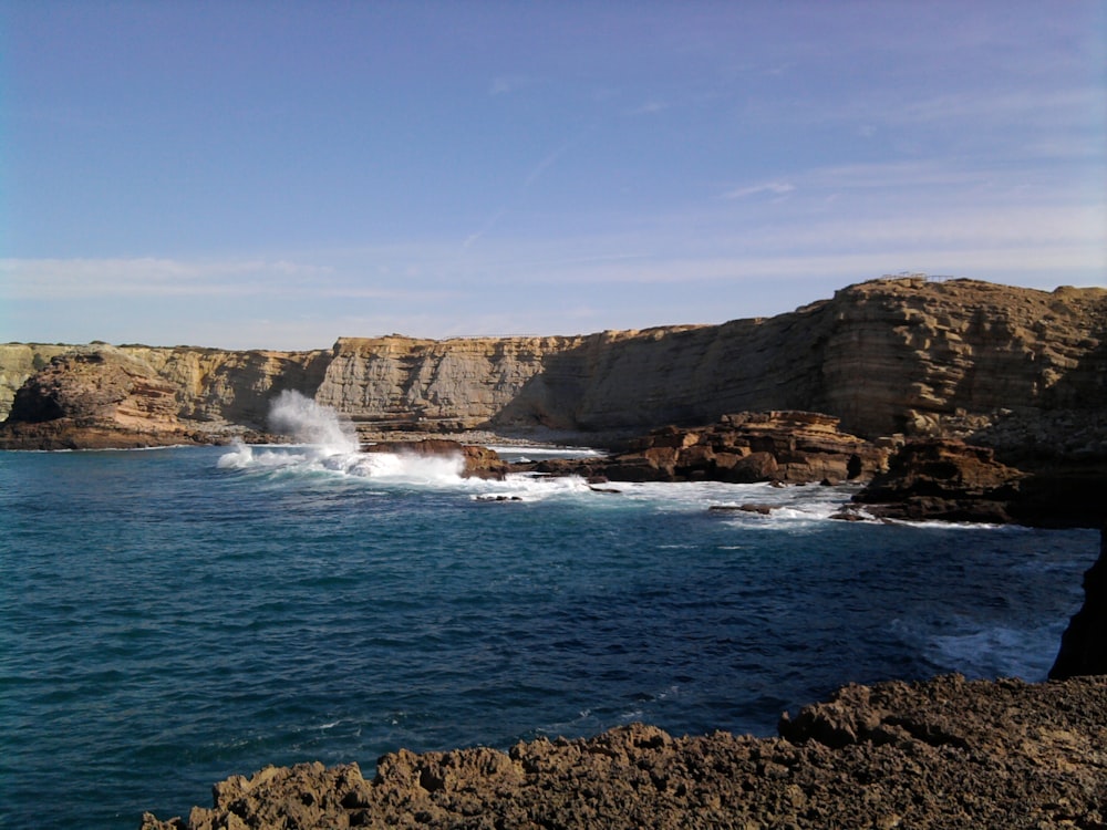 a rocky beach with a large body of water in the background