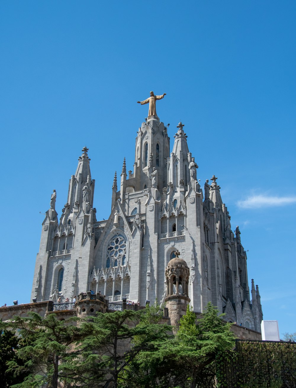a large building with a statue on top with Tibidabo in the background