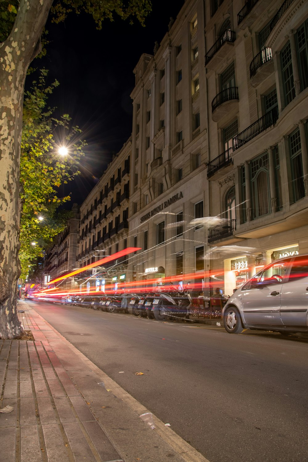 a street with a car parked on the side and a building with lights