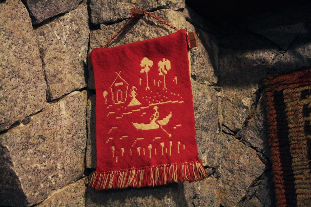 a red and white pillow on a stone surface