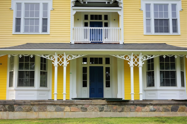Charming exterior of a small house with a pastel yellow facade and a welcoming front porch.