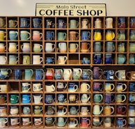 Set of personalized mugs with creative logos displayed on a rustic shelf.