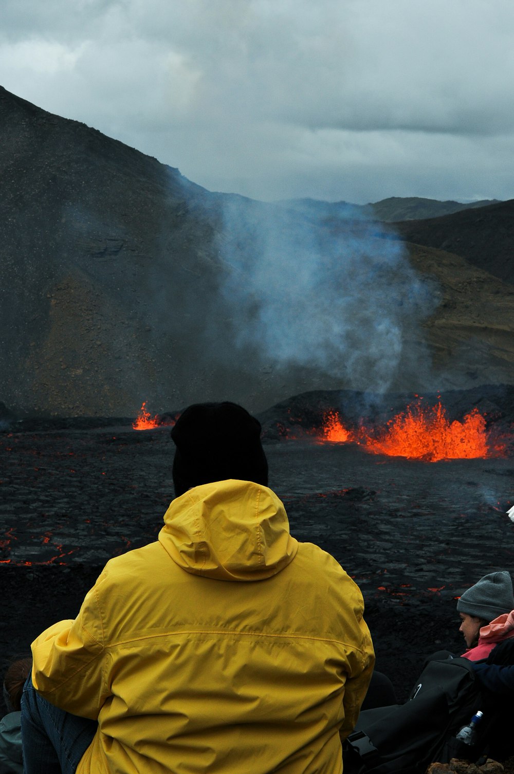 a group of people sitting on a boat in front of a volcano