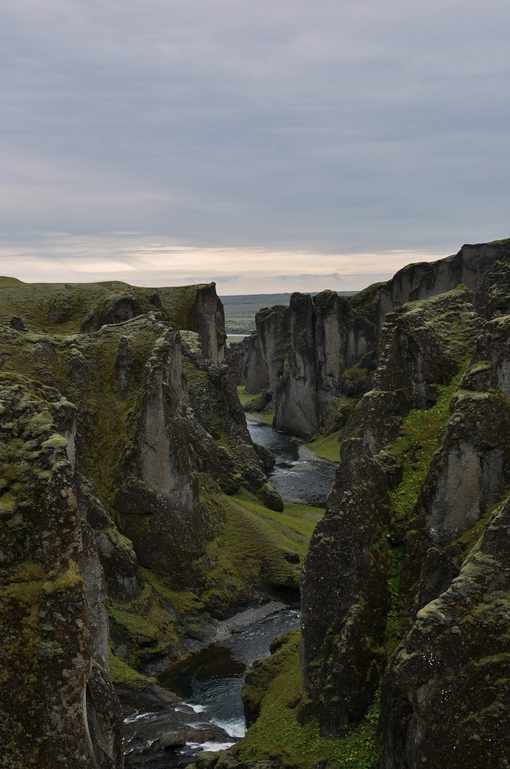 a rocky cliff side with a river running through it