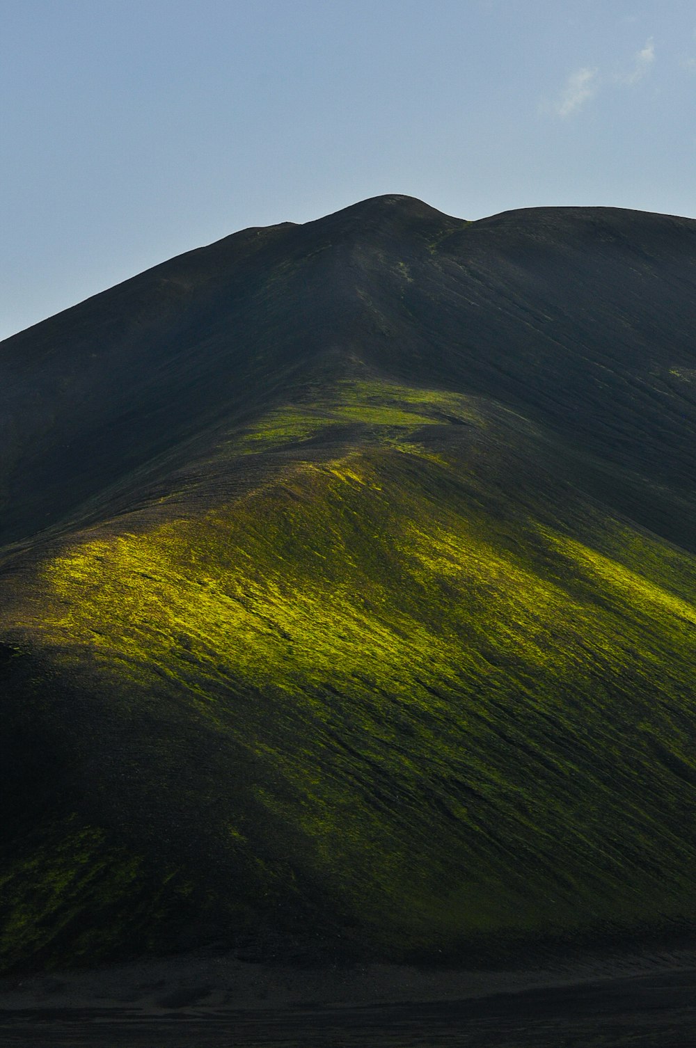 a green mountain with a blue sky