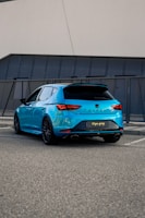 Modern black hatchback parked near a beach promenade.