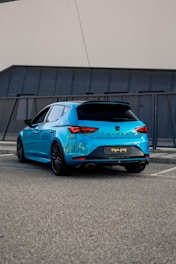 A compact hatchback parked in front of a modern urban building.