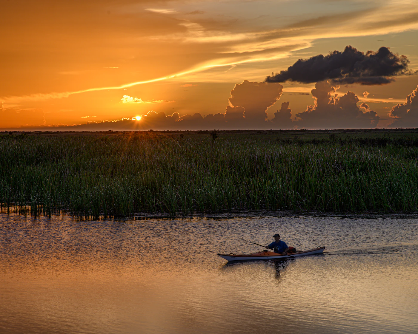A lone kayaker on marsh water at sunset. The Everglades begin just west of Davie and Southwest Ranches.