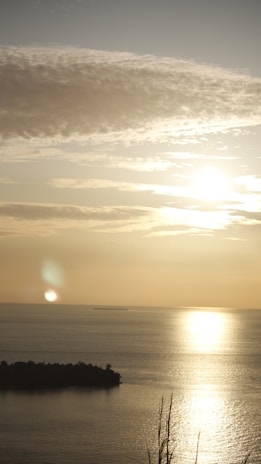 Sunset from the island shore casting golden light on the calm marine waters
