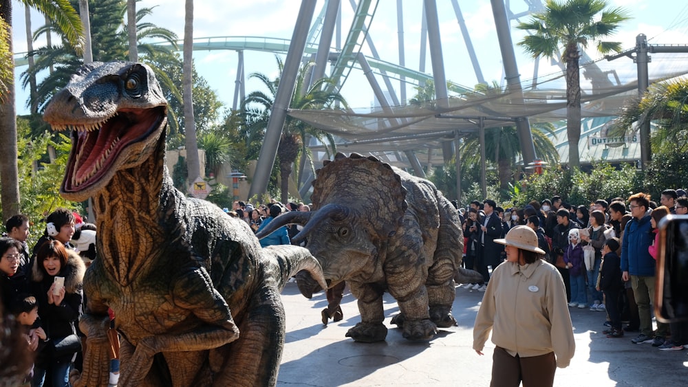 Una persona parada junto a una estatua de dinosaurio