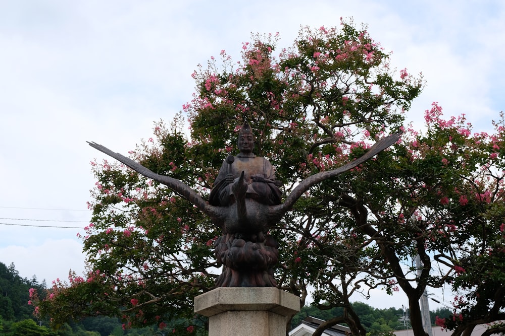 a statue of a person holding a branch with flowers on it