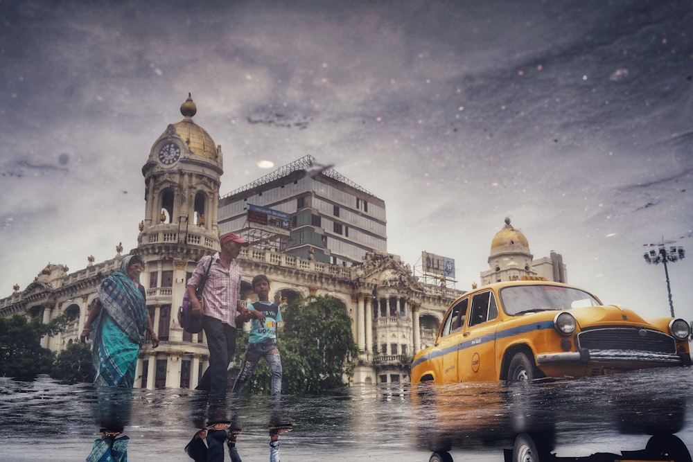 a group of people standing in a puddle of water next to a yellow car