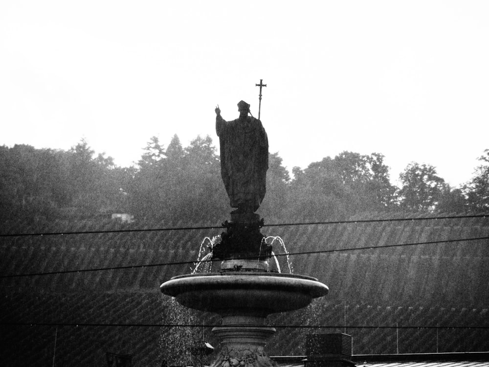 a statue of a person holding a cross on a fountain