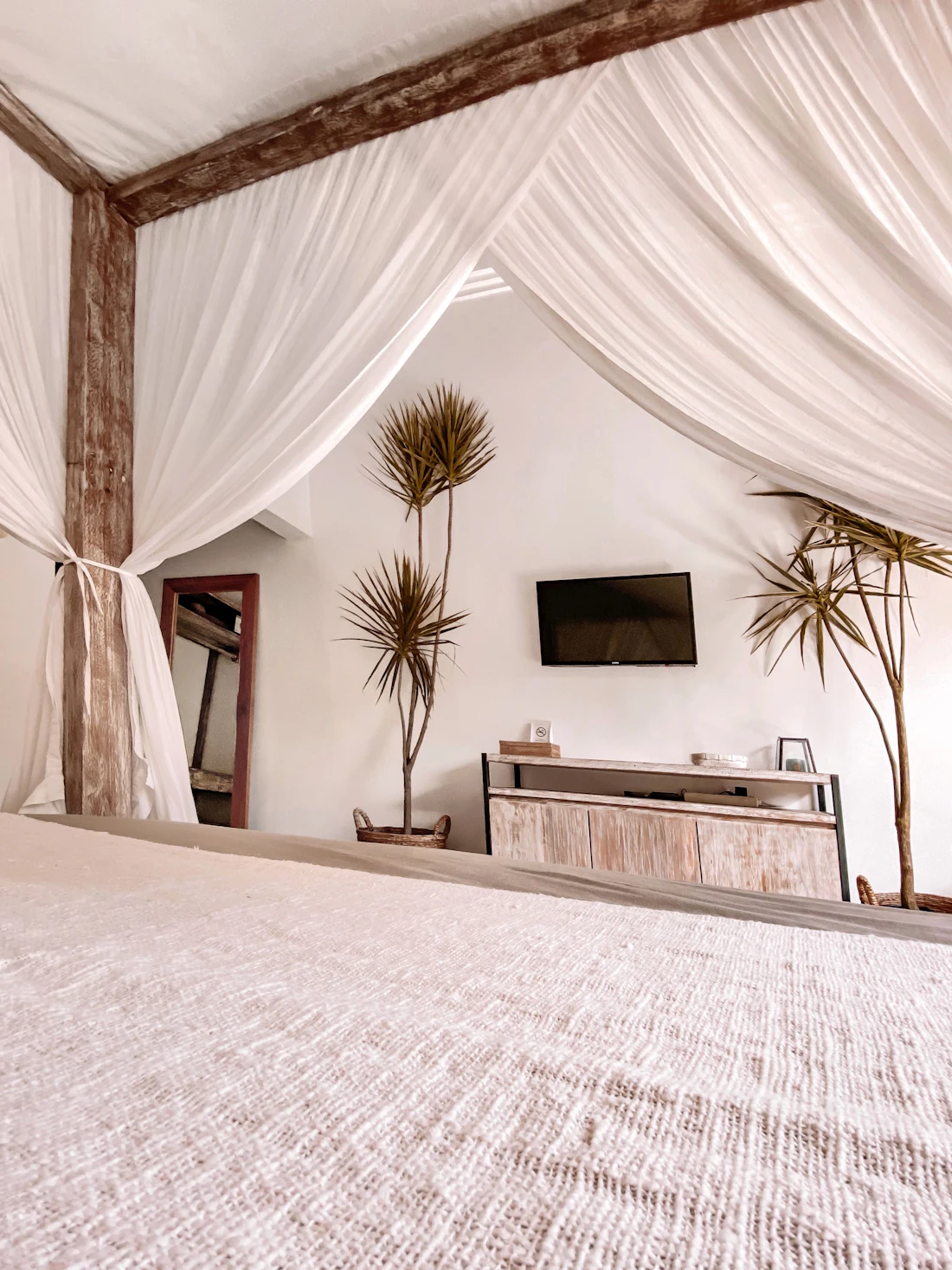 A canopy bed with sheer curtains, open to the garden