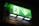 A green illuminated emergency exit sign displaying a pictogram of a person running towards an open door, alongside a downward-pointing arrow. The background around the sign is dark, highlighting the brightness of the sign.