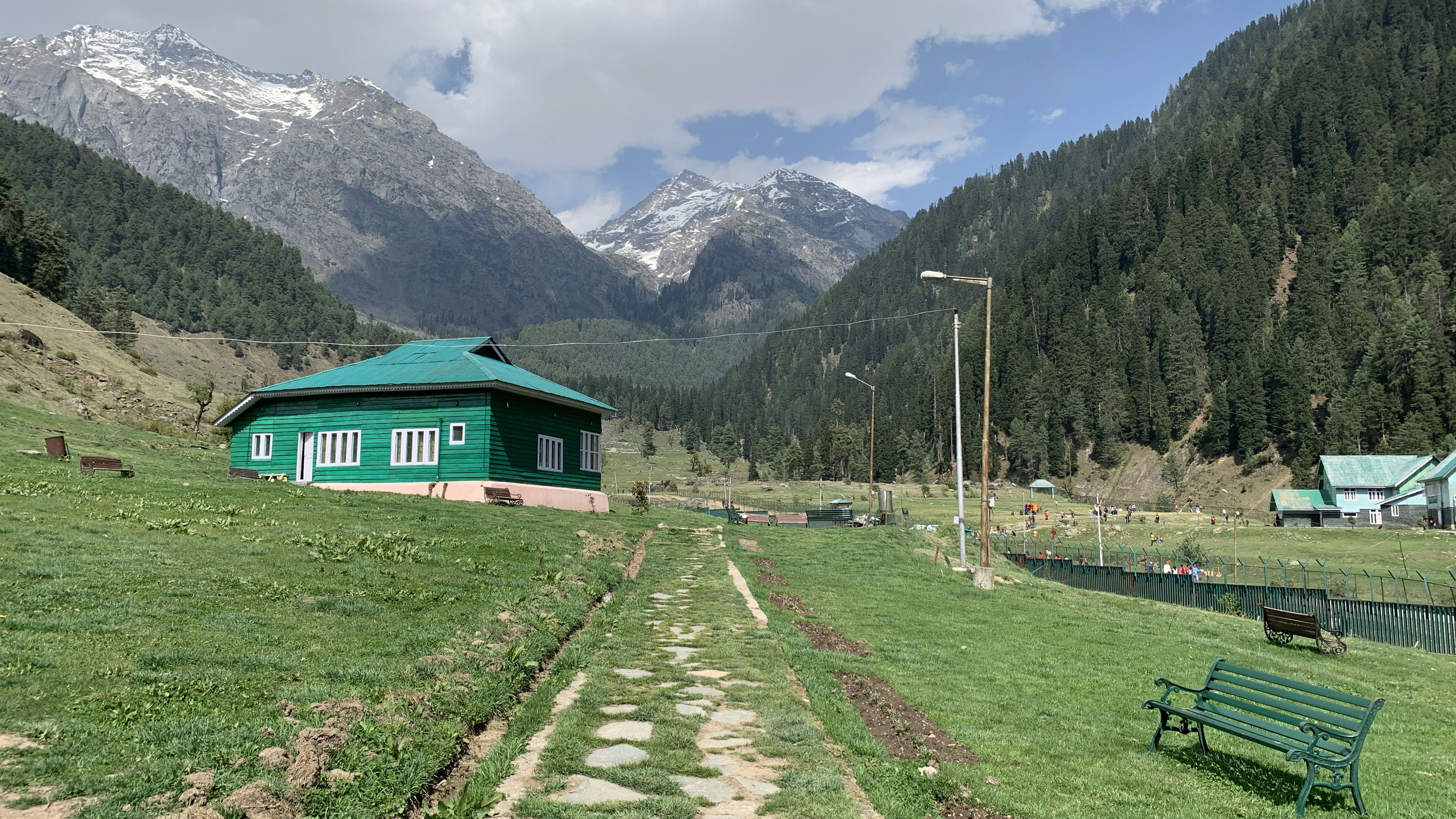 a small green house in a valley between mountains