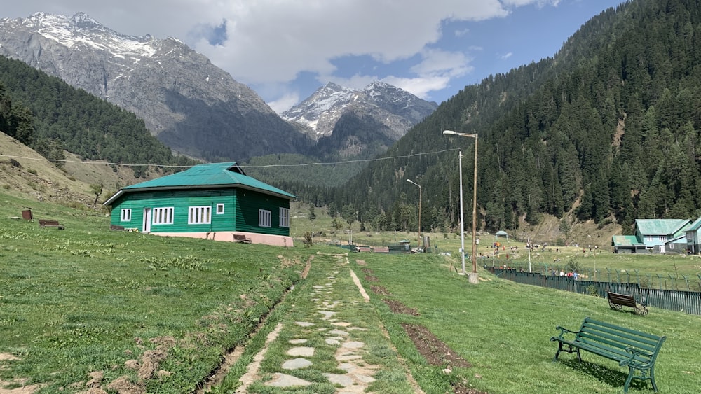 a small green house in a valley between mountains