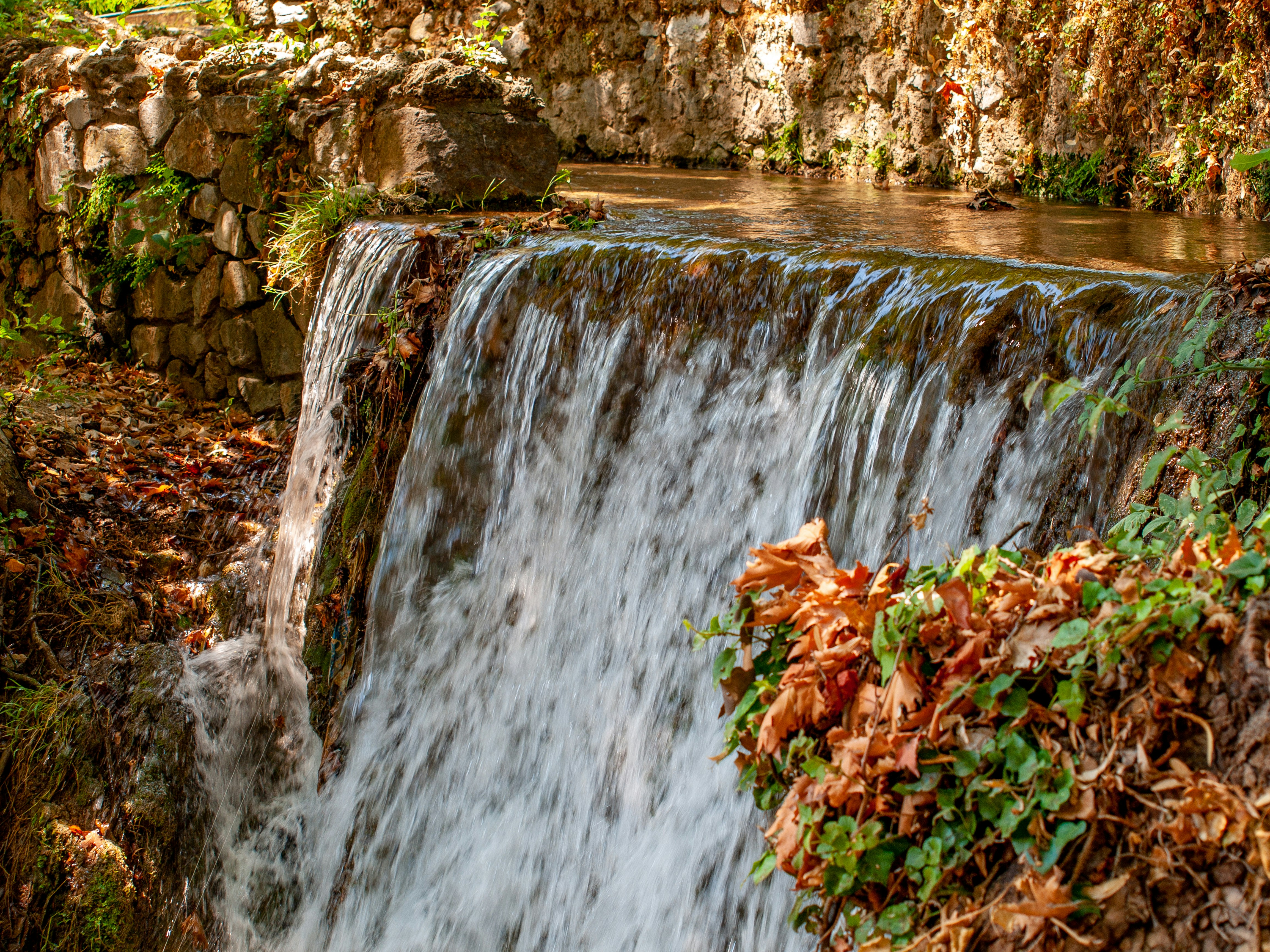 a waterfall with a rock wall