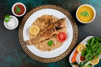 Grilled fish served on a rustic wooden board with lime wedges and a side of rice.