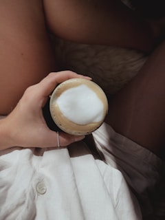 Portrait of Liam, holding a cappuccino with a playful grin, surrounded by coffee beans.