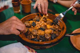 Mains qui partagent un tajine aux pruneaux