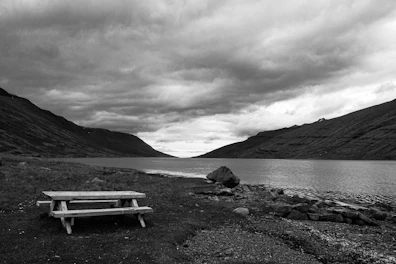 Close-up of a waterproof picnic mat rolled up beside a sparkling lake shore.