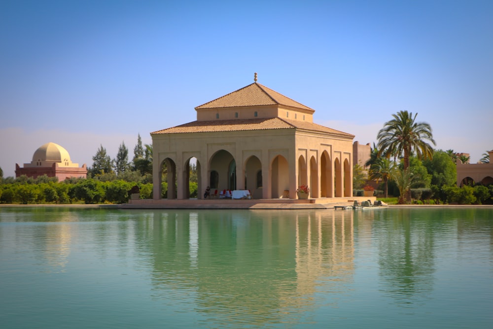 a building with a dome and columns by a body of water