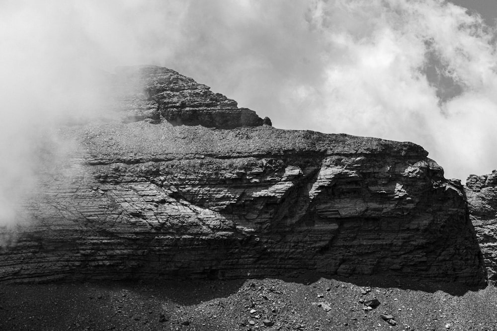 a rocky cliff with clouds above