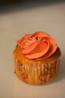 A beautifully decorated vanilla cupcake with swirls of pink frosting and edible flowers.