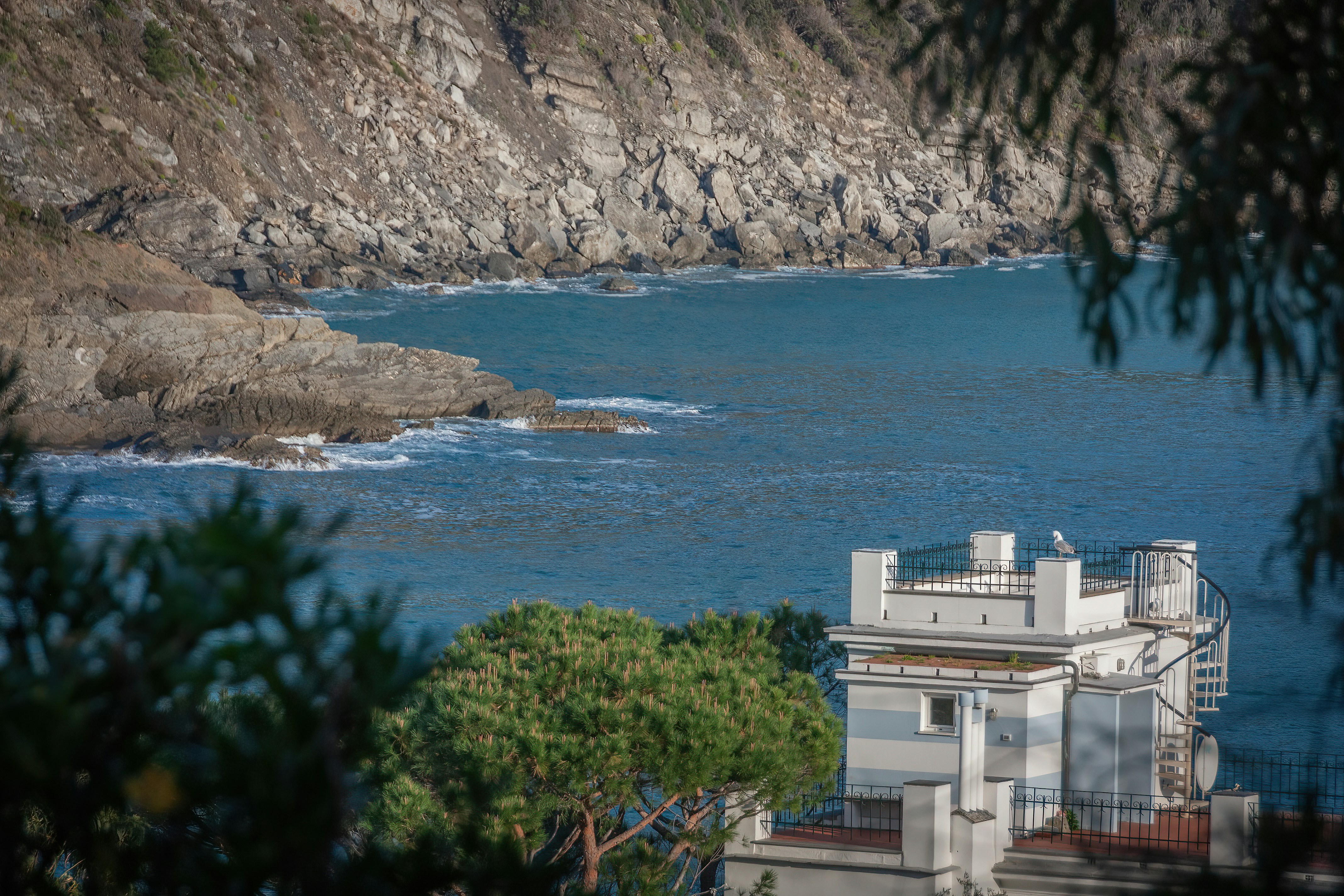 A building on a cliff overlooking a body of water photo - Free Sestri ...