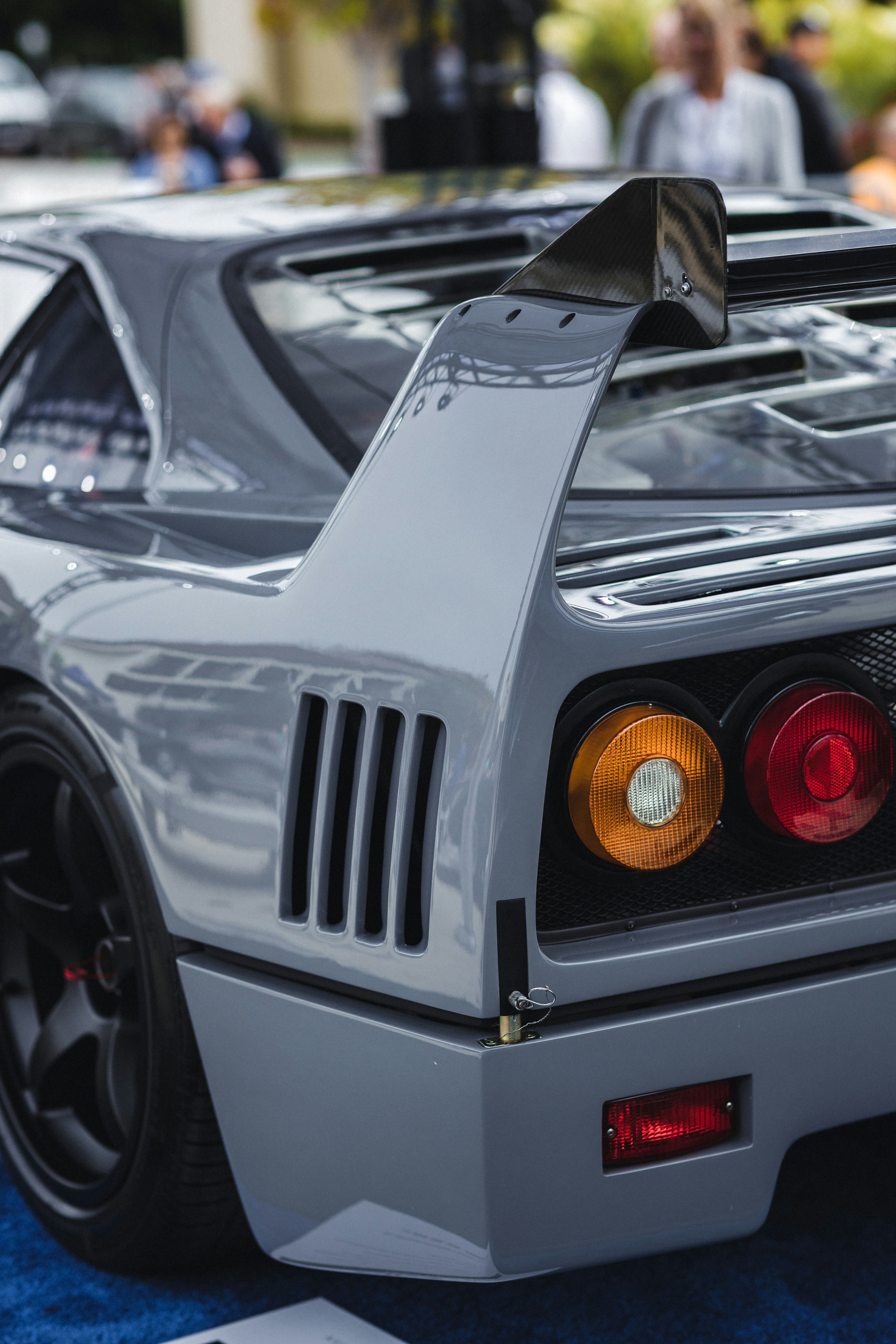 Ferrari F40 side profile showing iconic wedge shape, NACA ducts, and rear wing at a classic car show