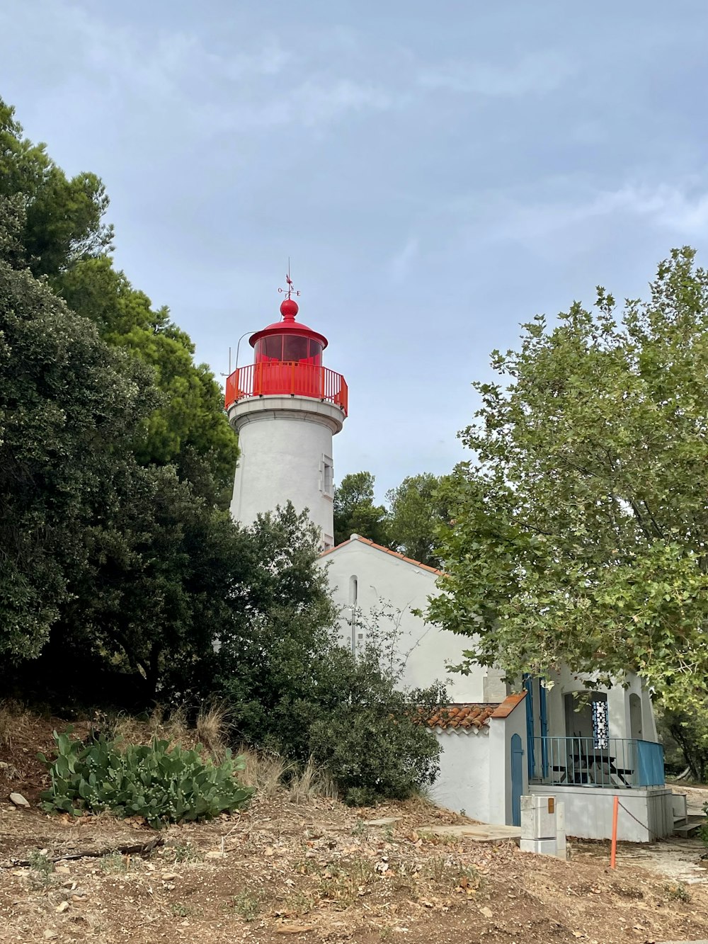 a white building with a red and white tower surrounded by trees