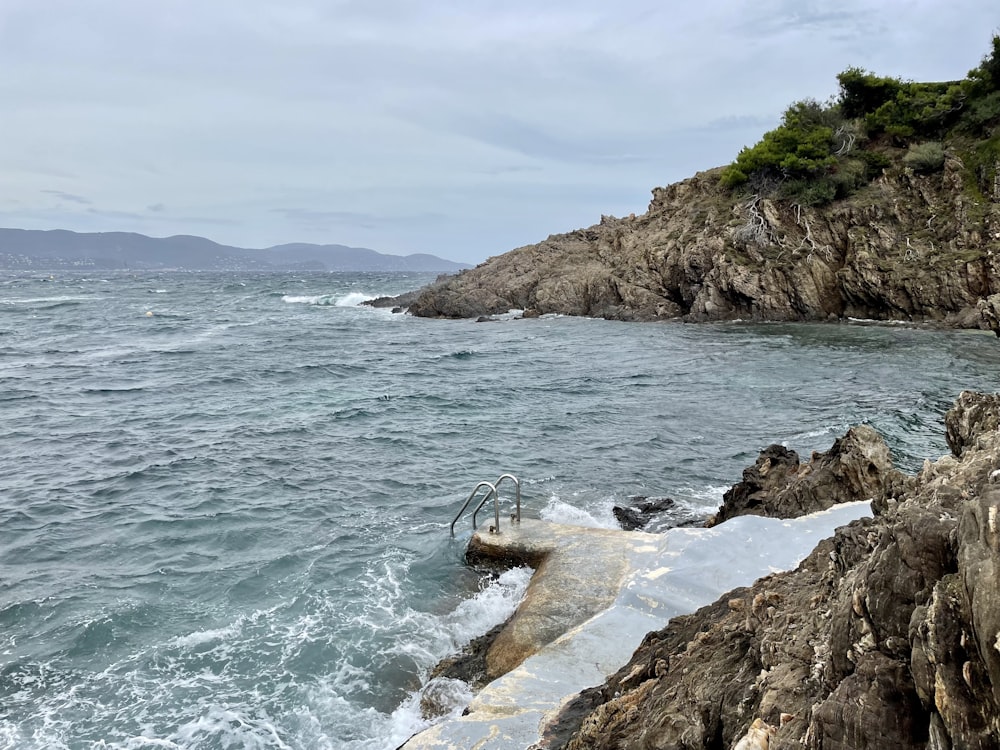 a rocky beach with a body of water and a rocky cliff