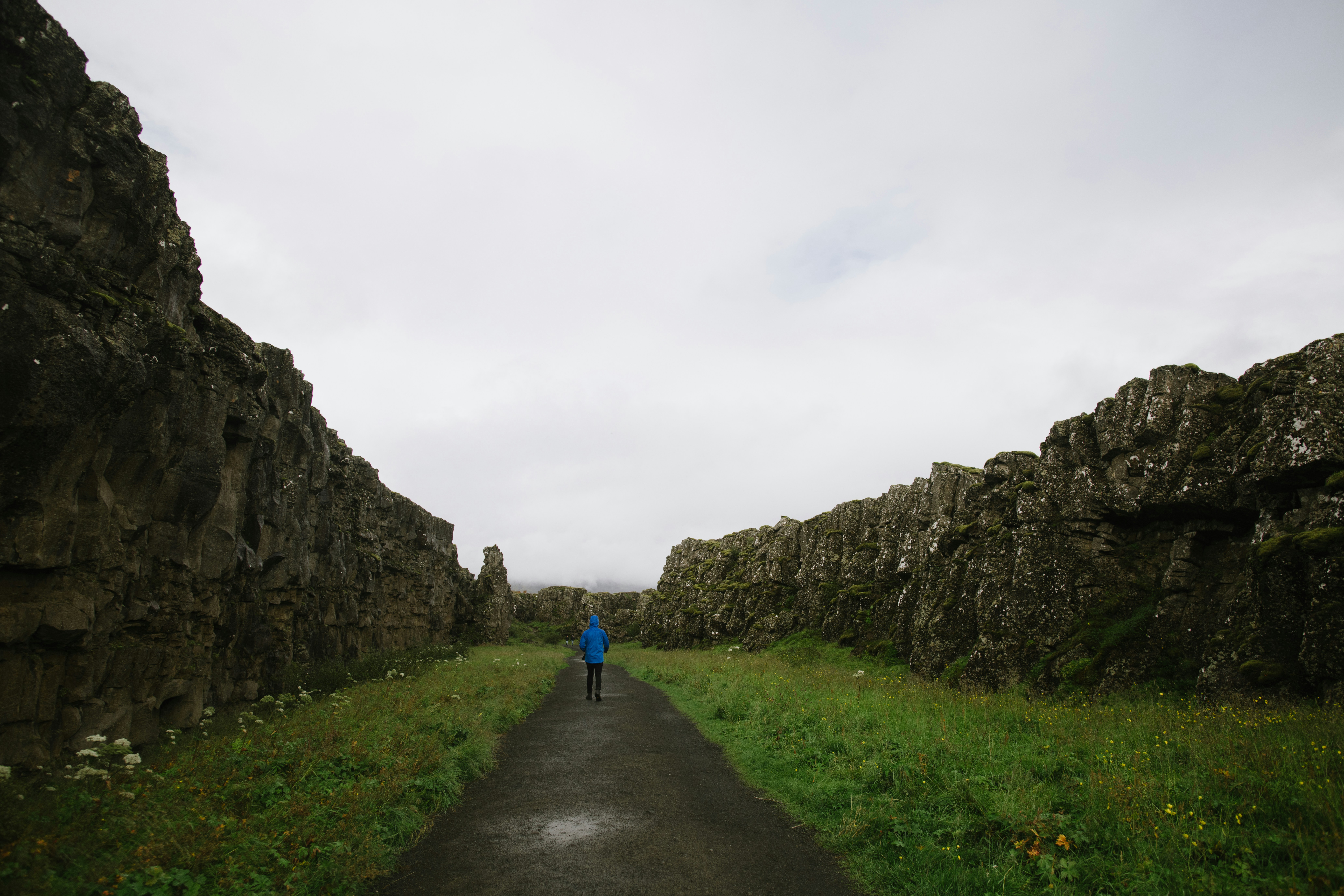 a person walking on a path between stone walls