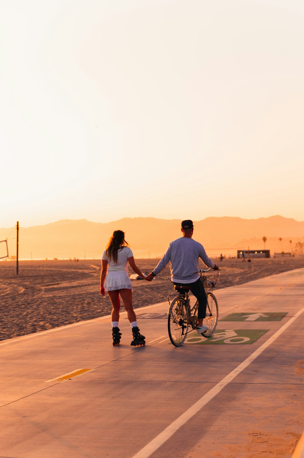 a man and a woman walking on a road with a bicycle