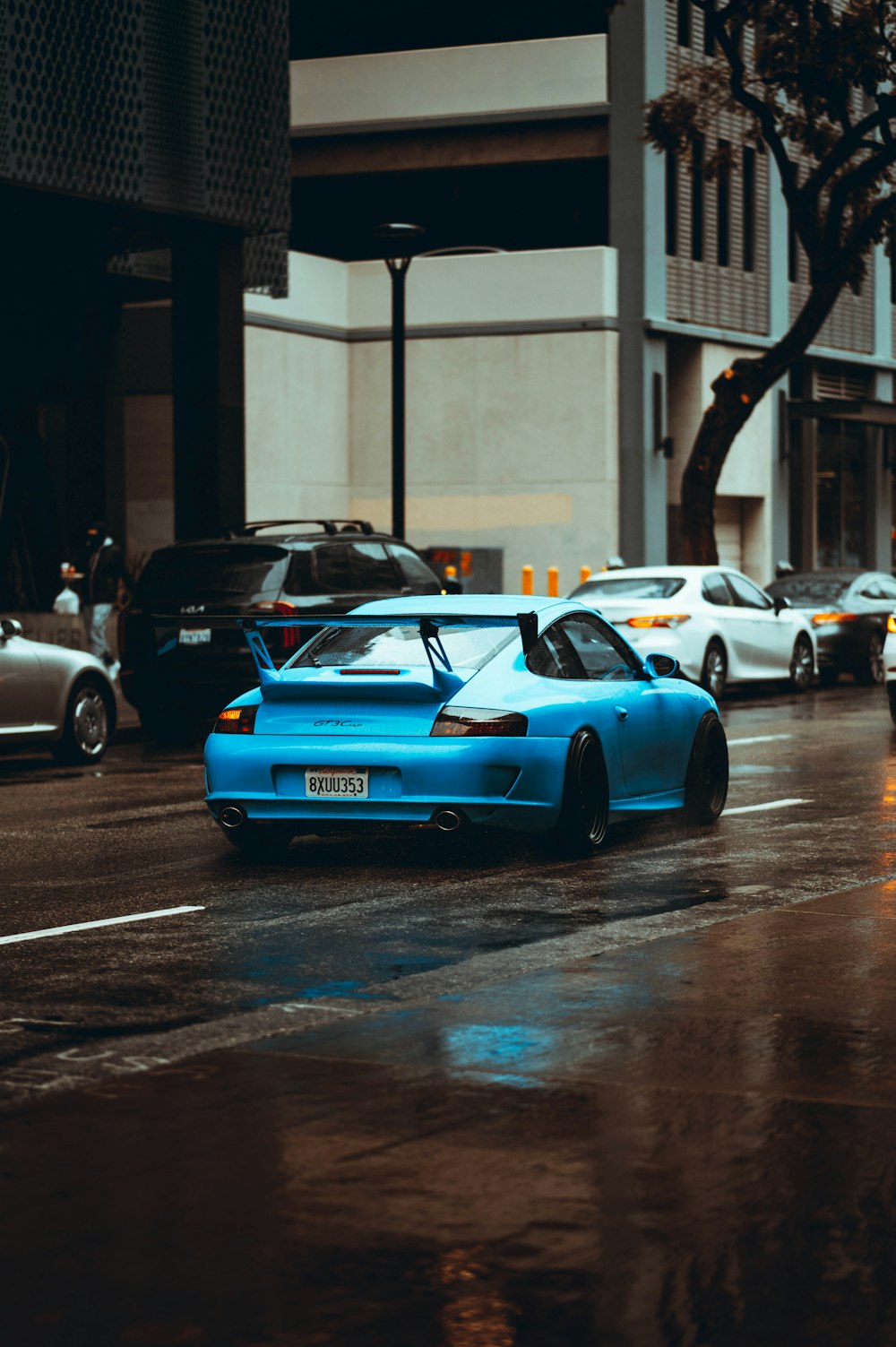 a blue sports car on a wet street