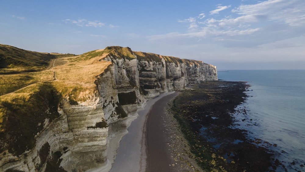 a cliff side with a beach and ocean below