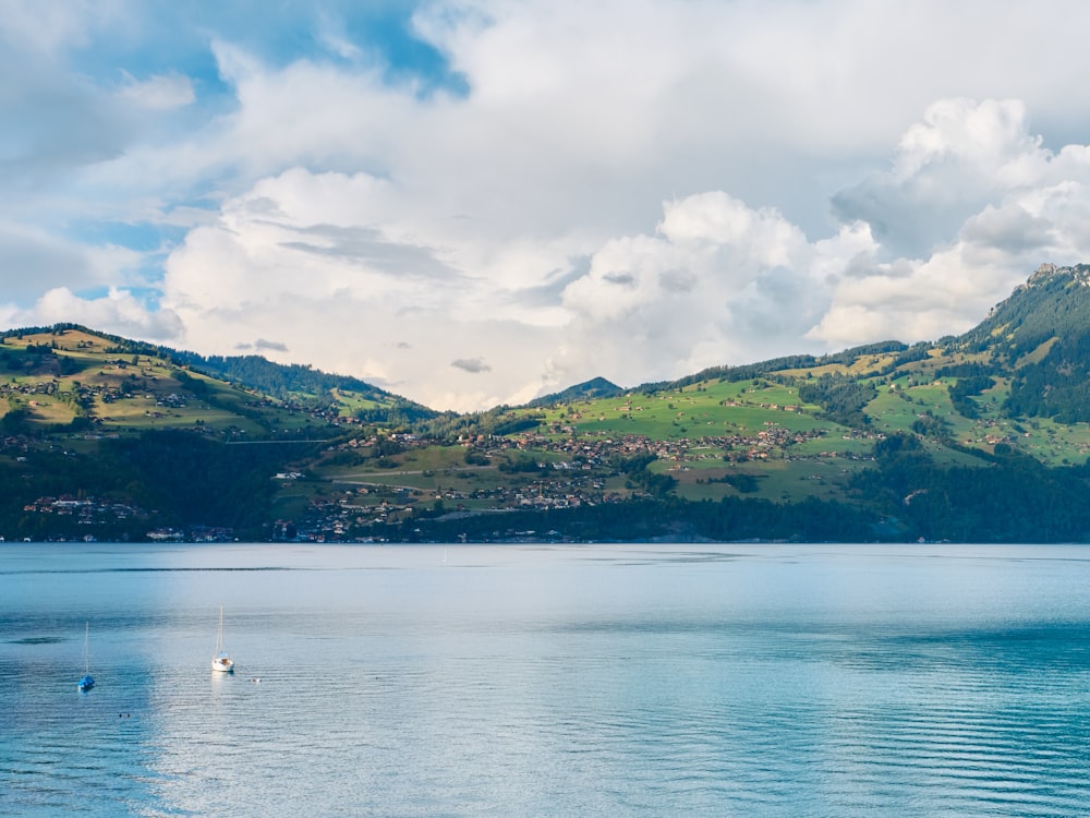 a body of water with boats in it and hills in the back