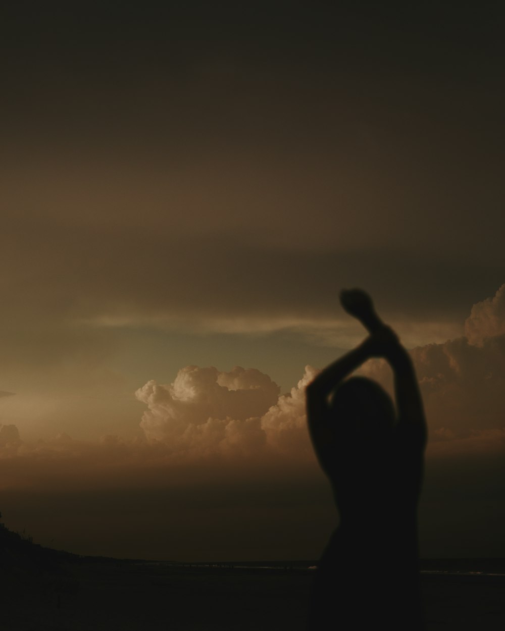 a person holding the hand up in front of a sunset