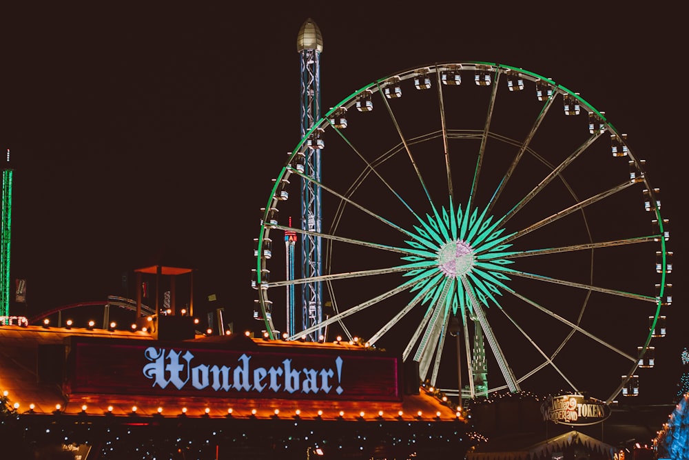 a ferris wheel at night with Cosmo Clock 21 in the background