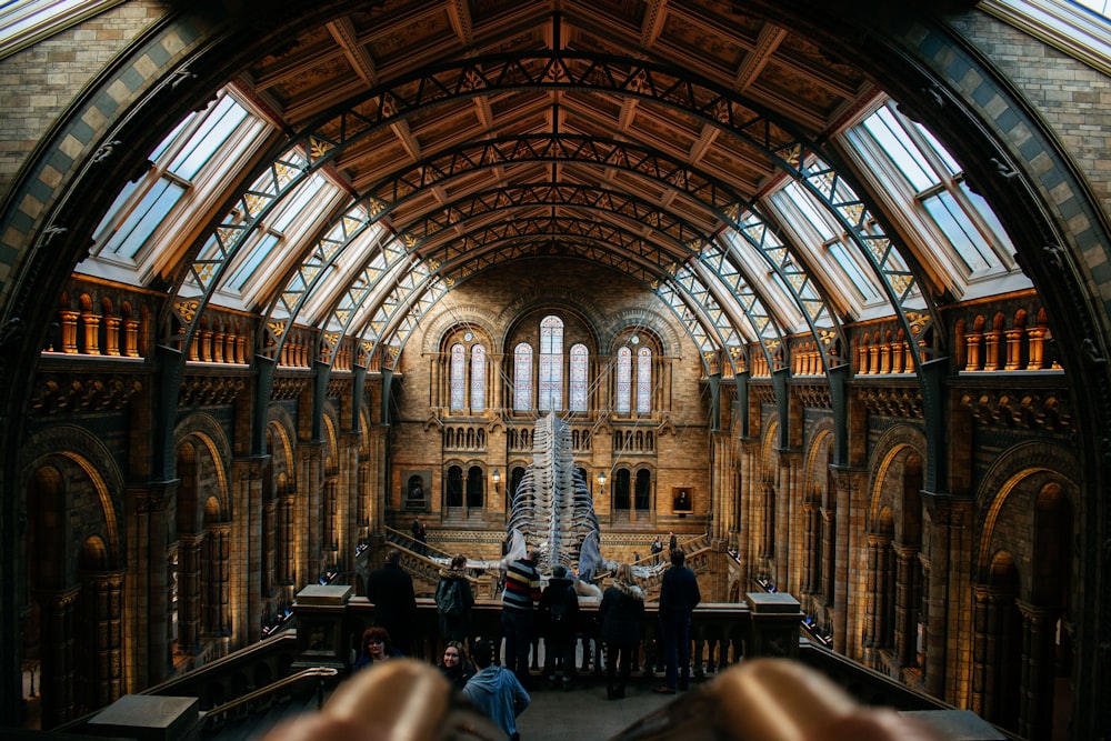 a large room with a statue in it and people in it with Natural History Museum in the background