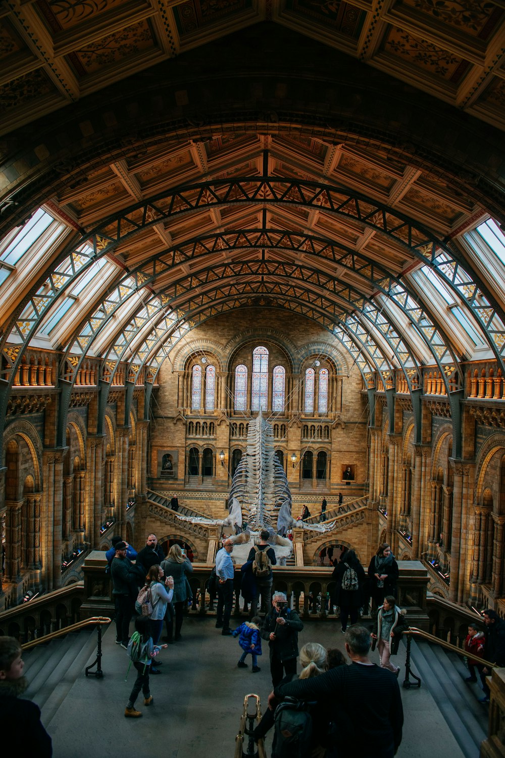 a large room with a statue in it and people in it with Natural History Museum in the background